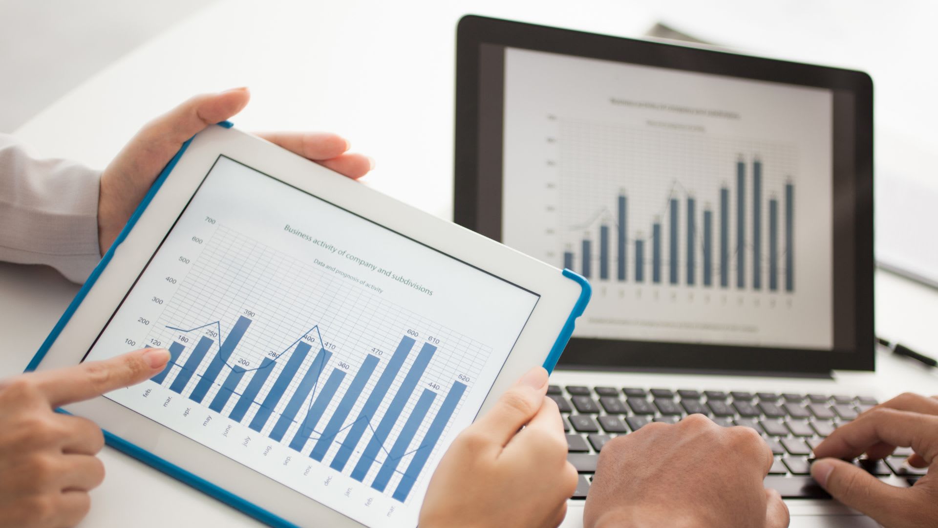 Two individuals analyzing graphs on a tablet.