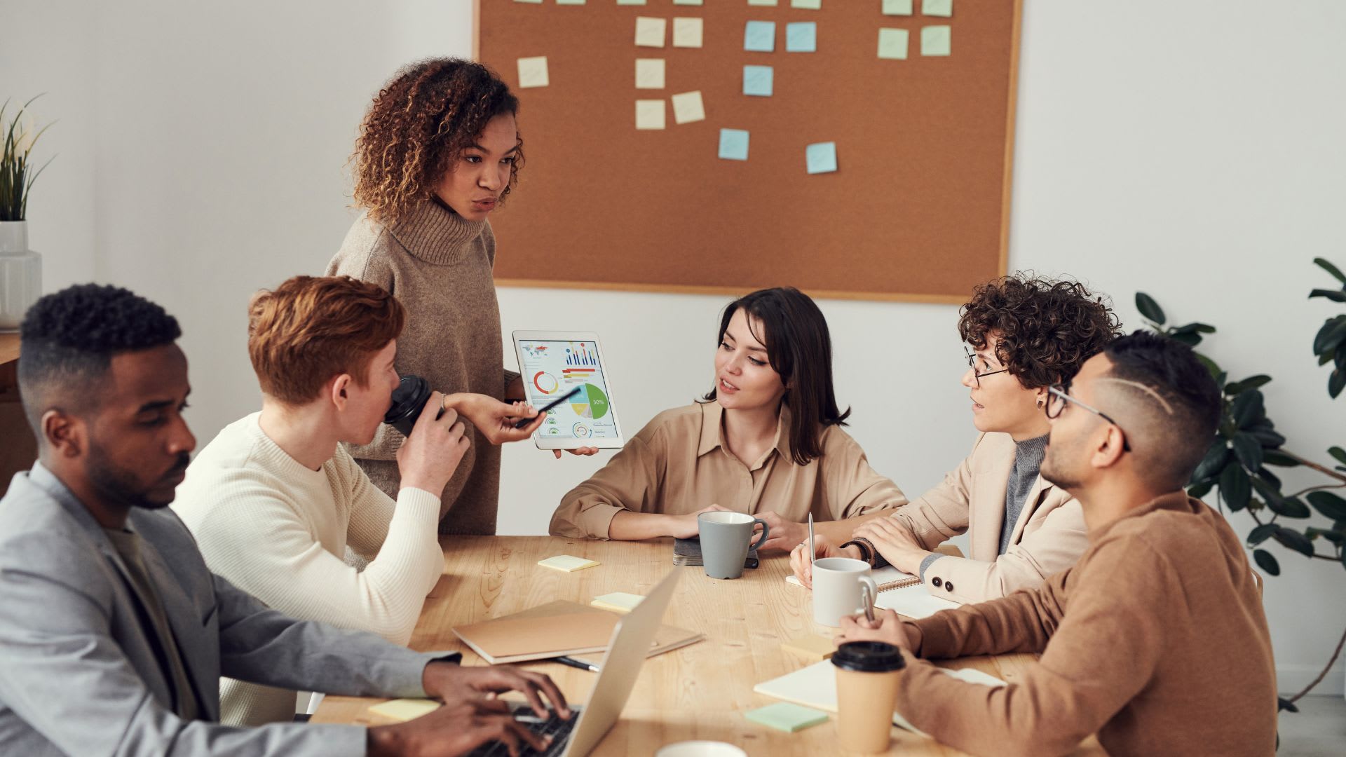 A woman leading a meeting with a group of individuals seated around a conference table.