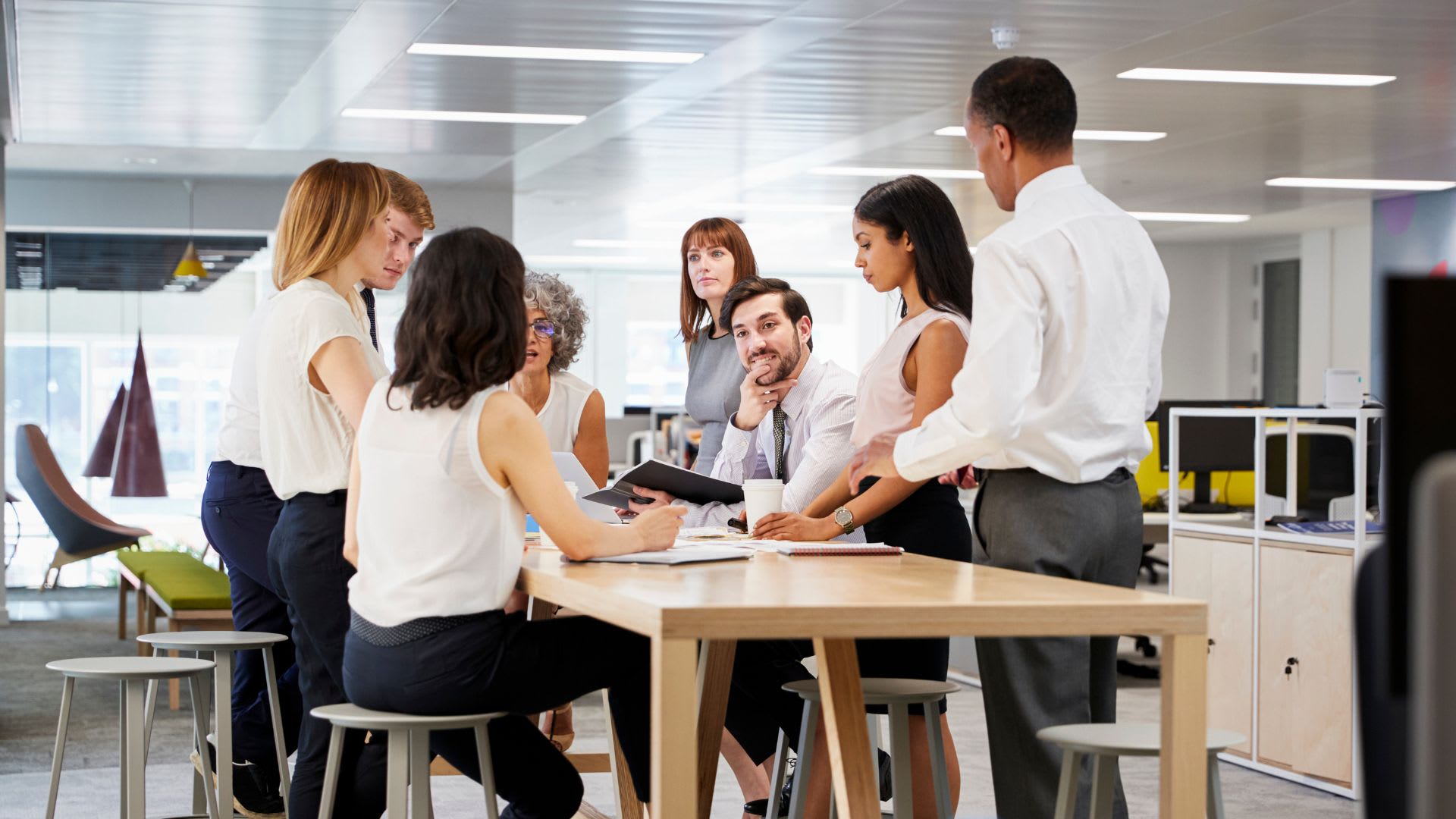 A diverse group of individuals gathered around a table engaged in a discussion or meeting.