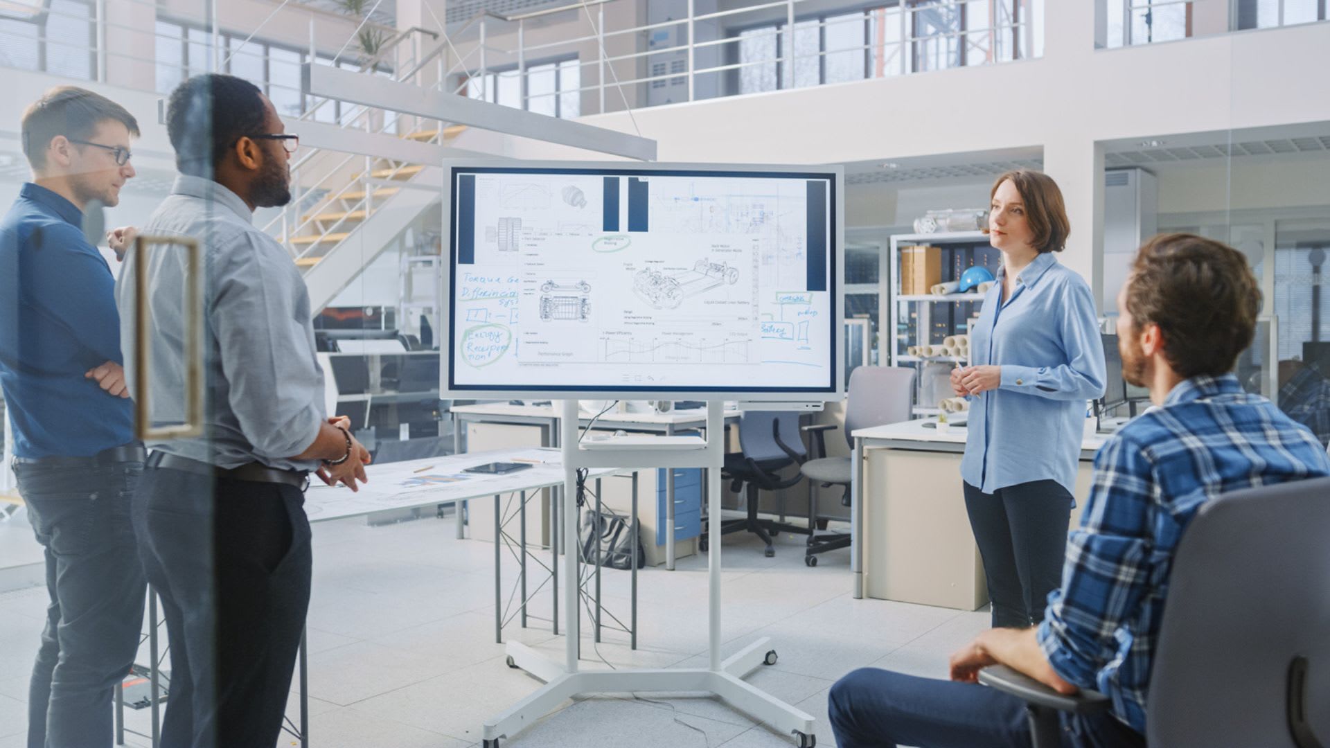 Office workers gathered around a digital whiteboard, engaged in a discussion or presentation.