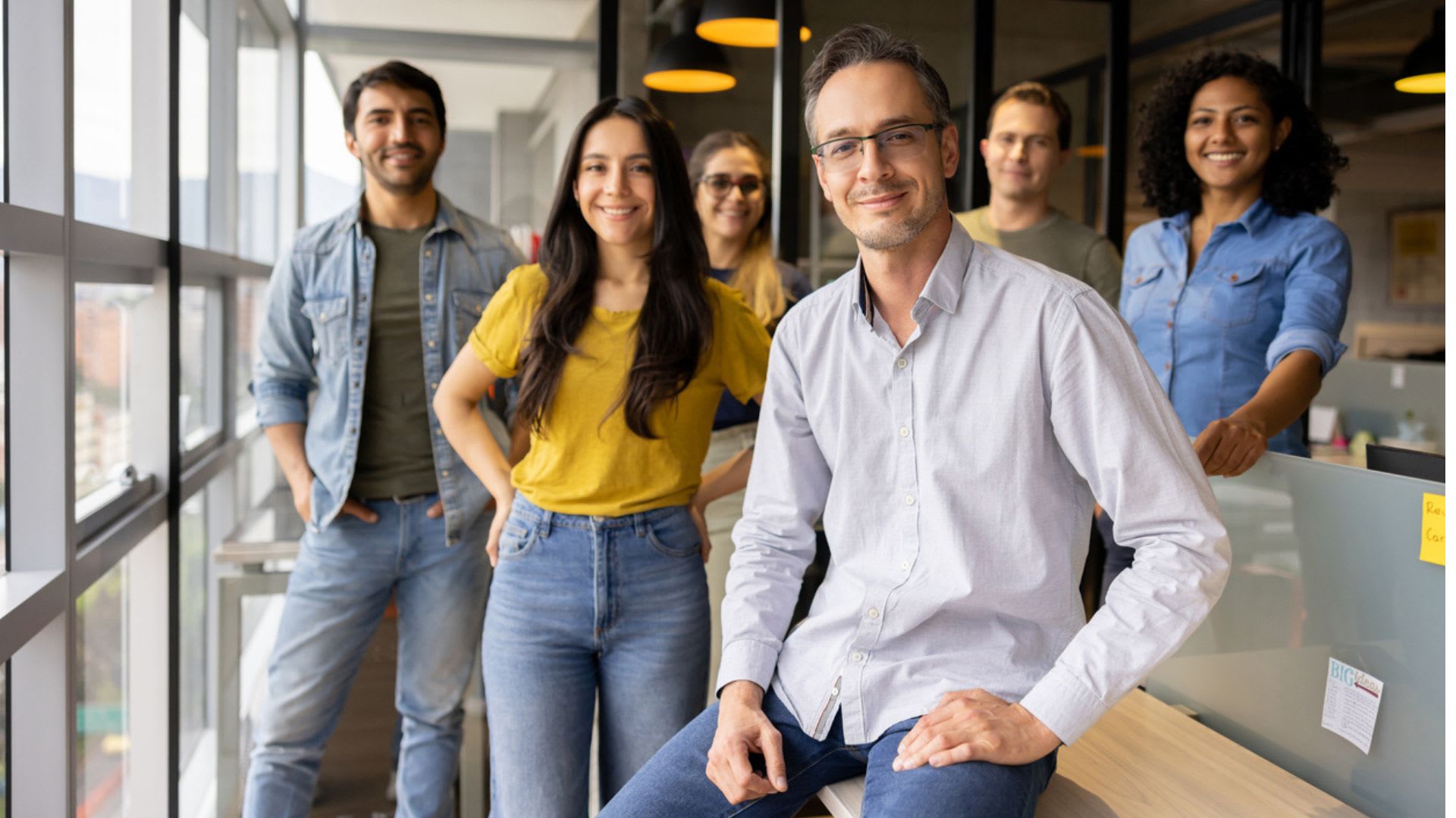 A group of professionals standing in a modern office setting, smiling.