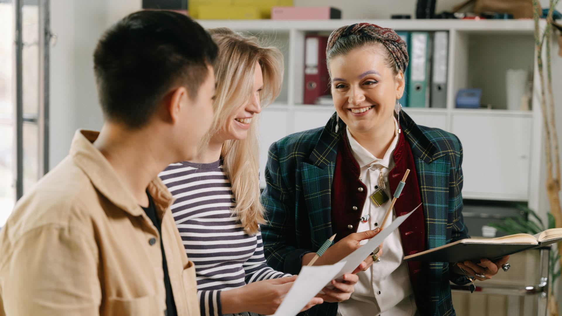 Three people engaged in a conversation in an office setting.