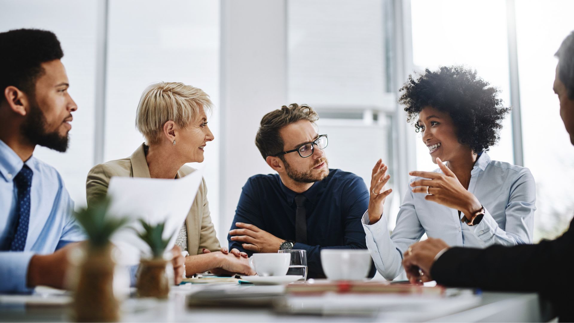 A group of business professionals engaged in a discussion while seated around a table.