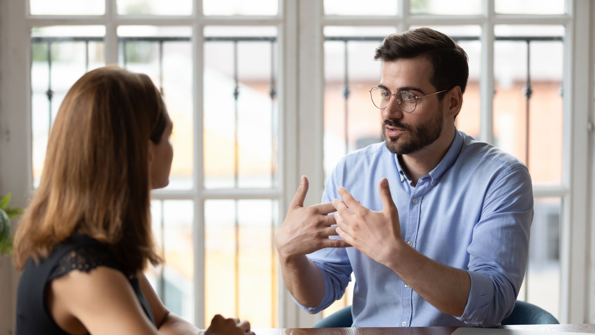 A man and woman engaged in conversation at a table, deep in discussion.