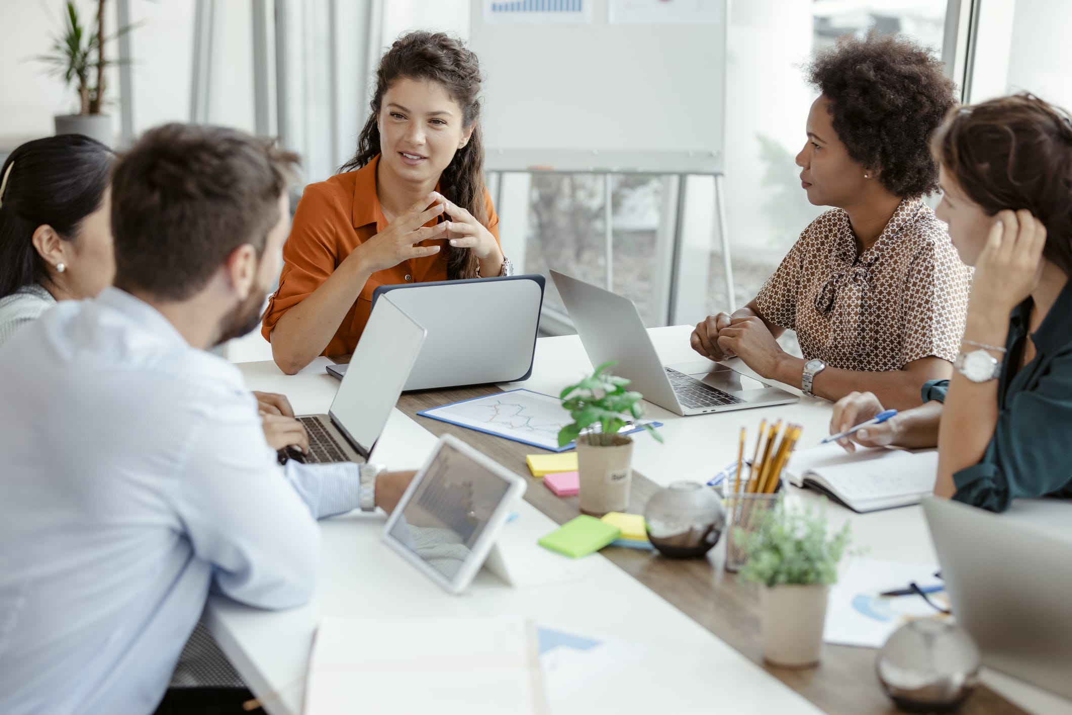 A diverse group of individuals sitting around a table, engrossed in their work on laptops.