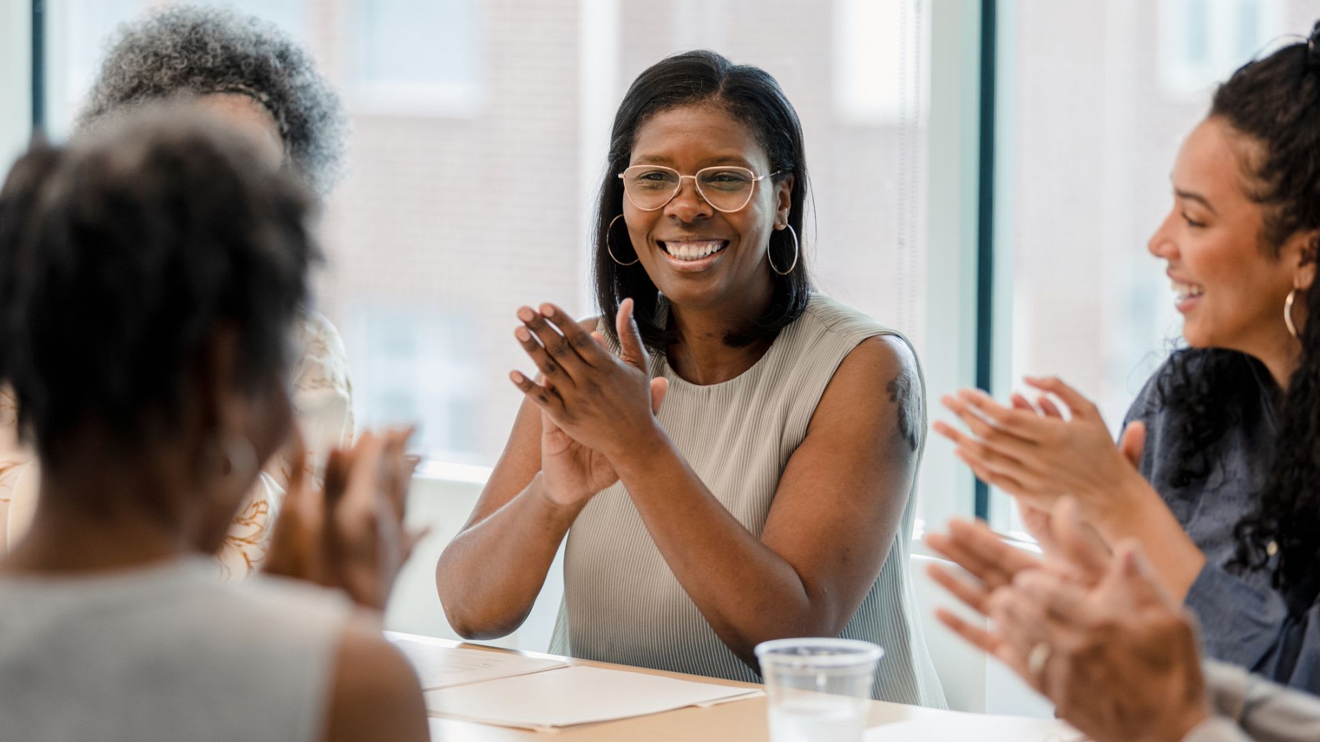 People on a diverse team applauding together at a meeting.