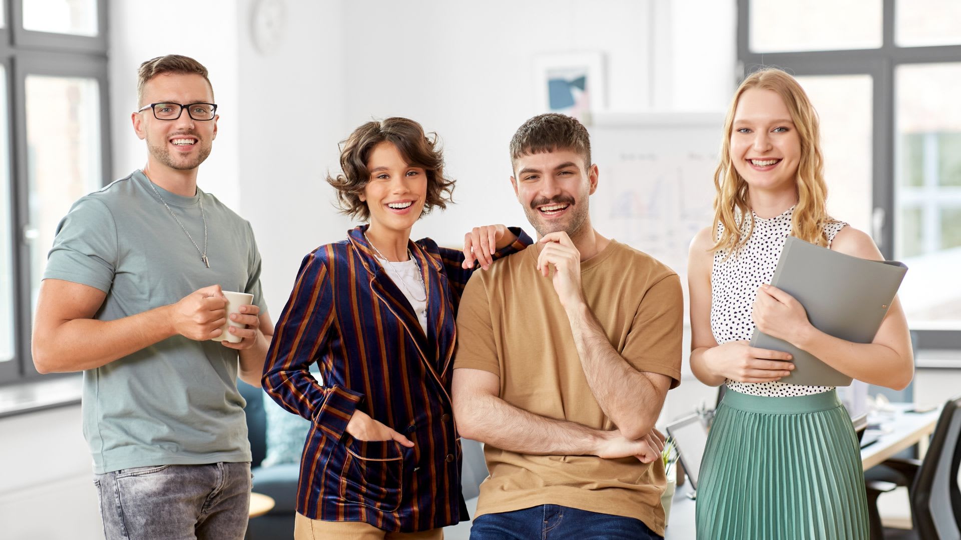 Four professionals standing in an office, one person smiling.