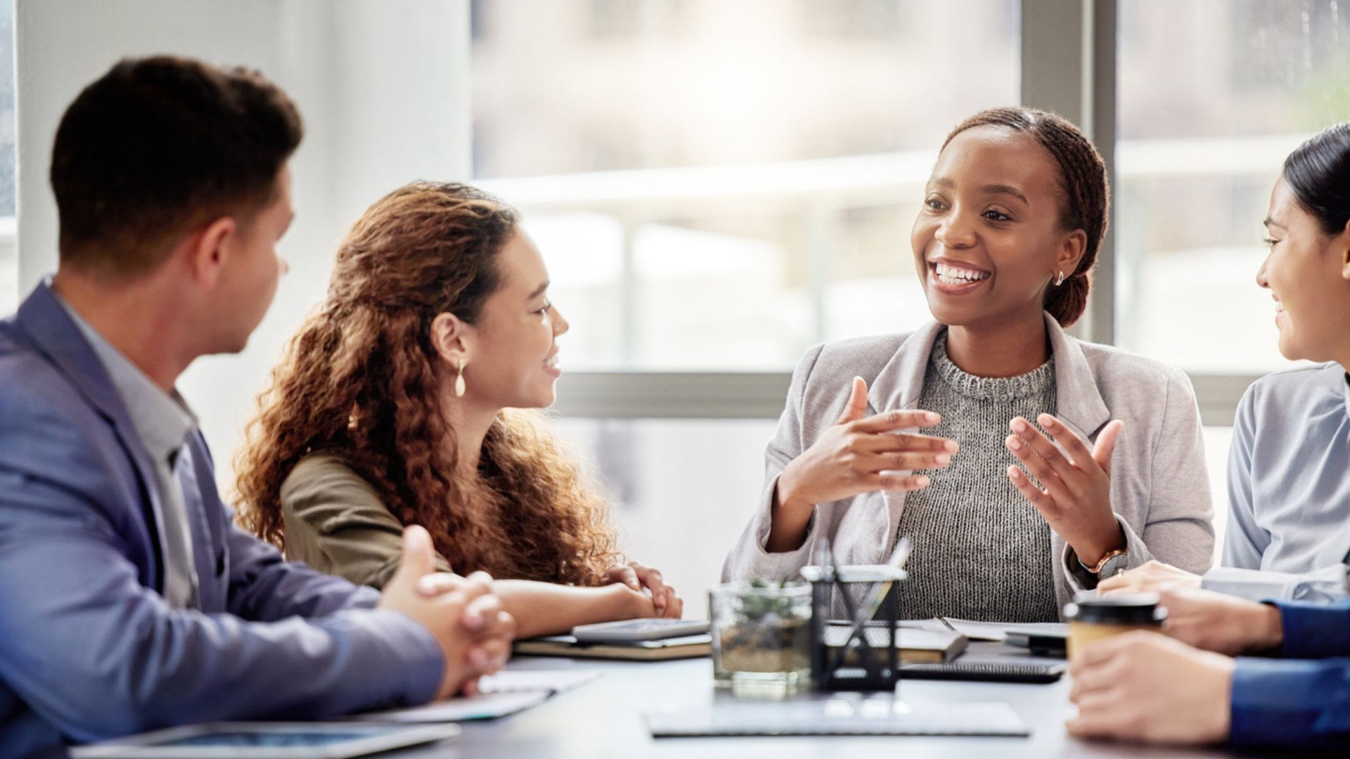 A diverse group of professionals engaged in a meeting, discussing business matters around a conference table.
