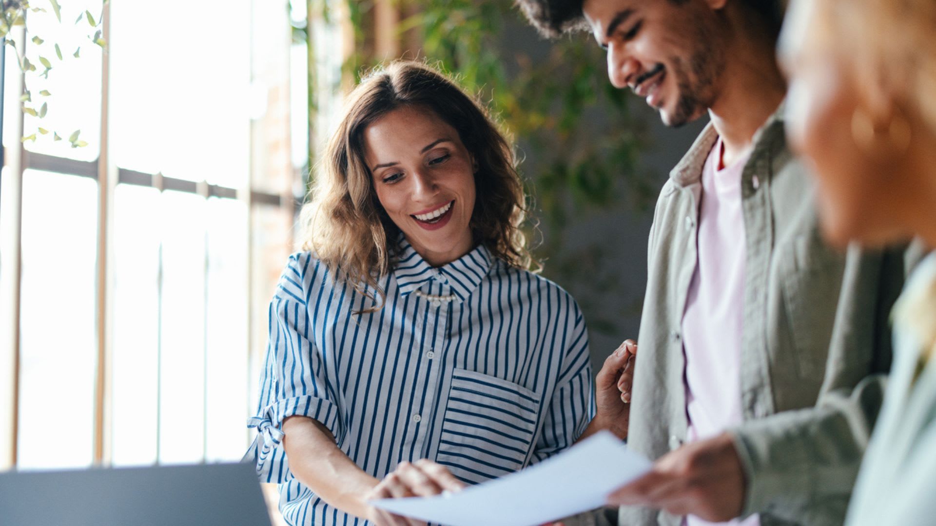 Office workers happily review a document, wearing smiles of satisfaction.