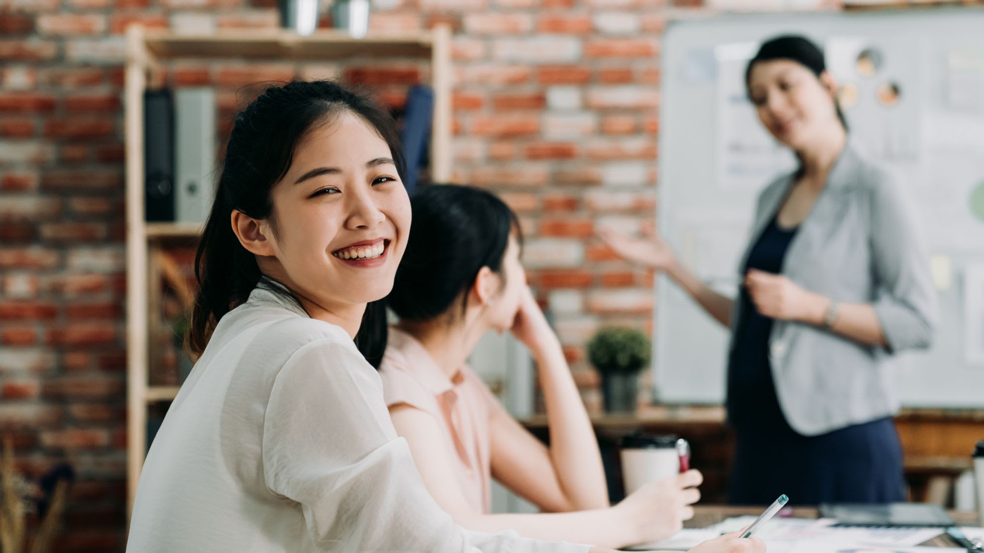 A woman smiling at desk in office.