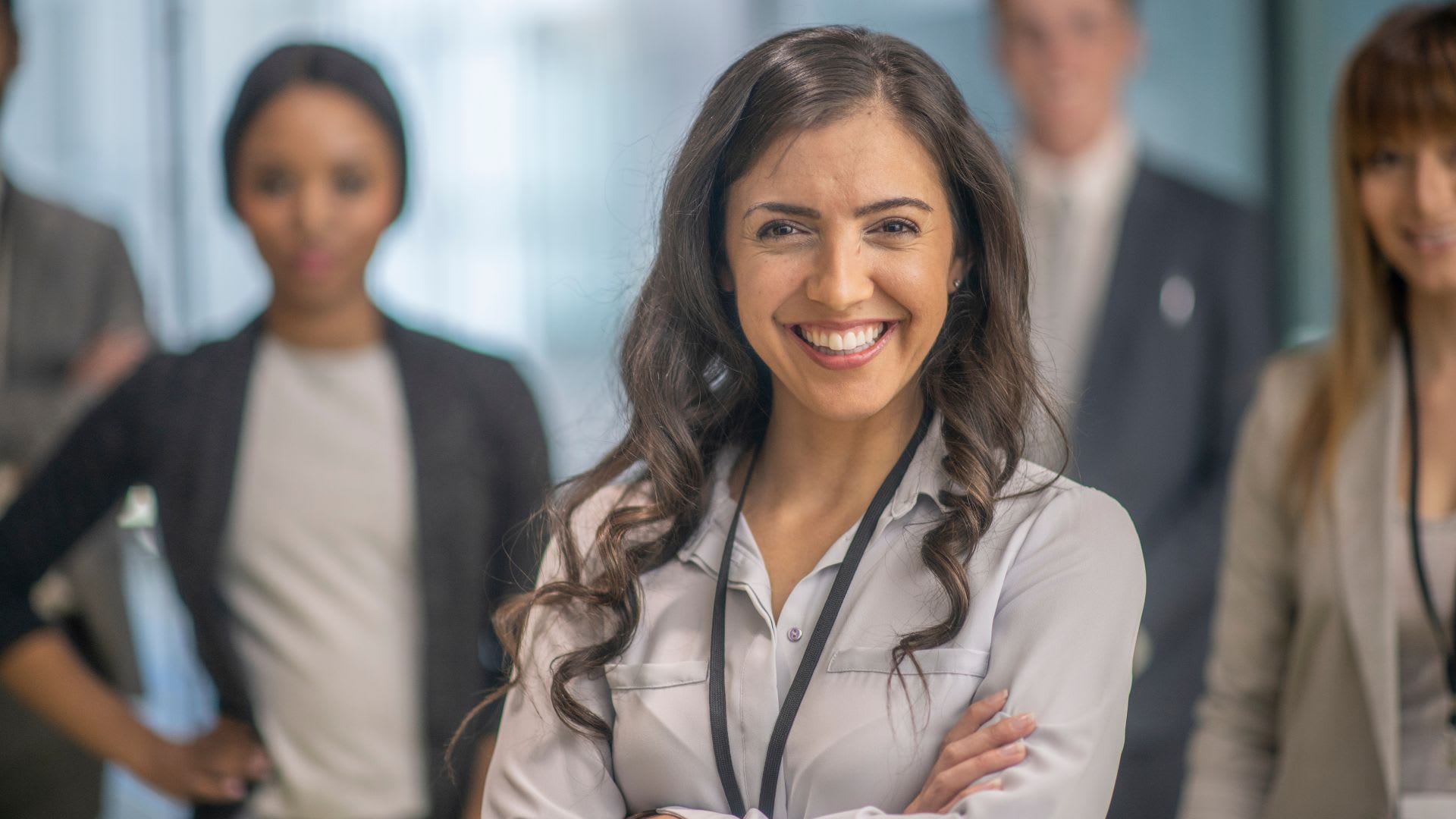  A woman stands in front of a group of business people, leading with poise and authority.