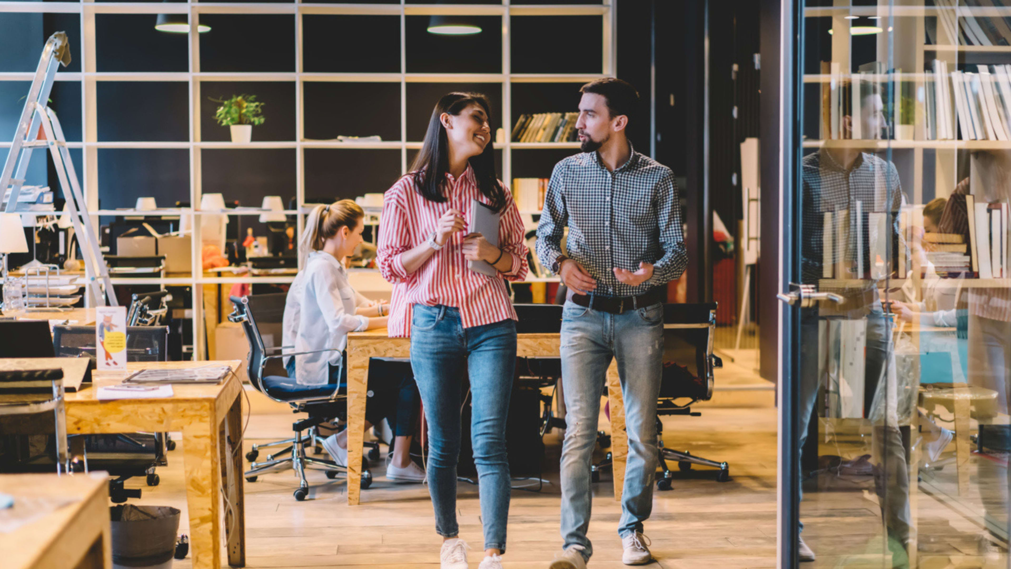 Two colleagues walking together in an office setting, highlighting teamwork and interaction in a corporate environment.