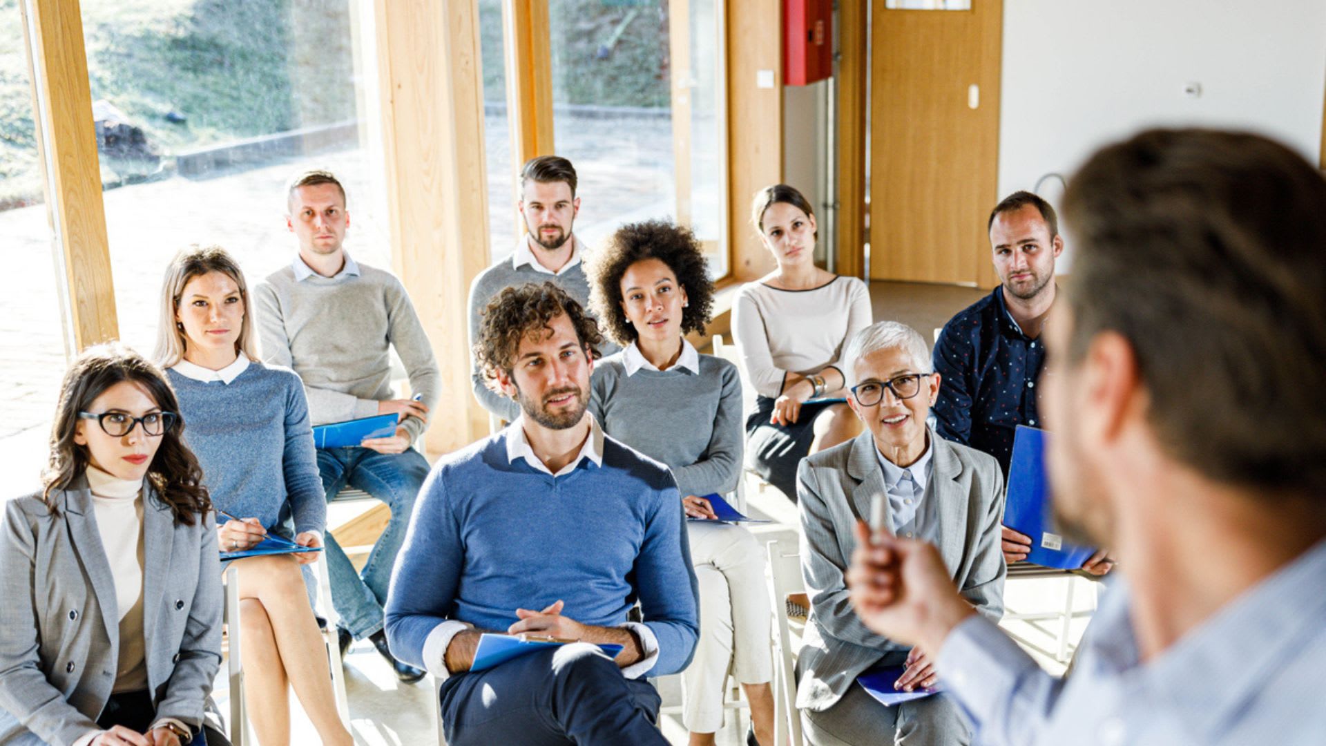 A gathering of people in a room focused on a speaker, highlighting an interactive discussion or presentation.