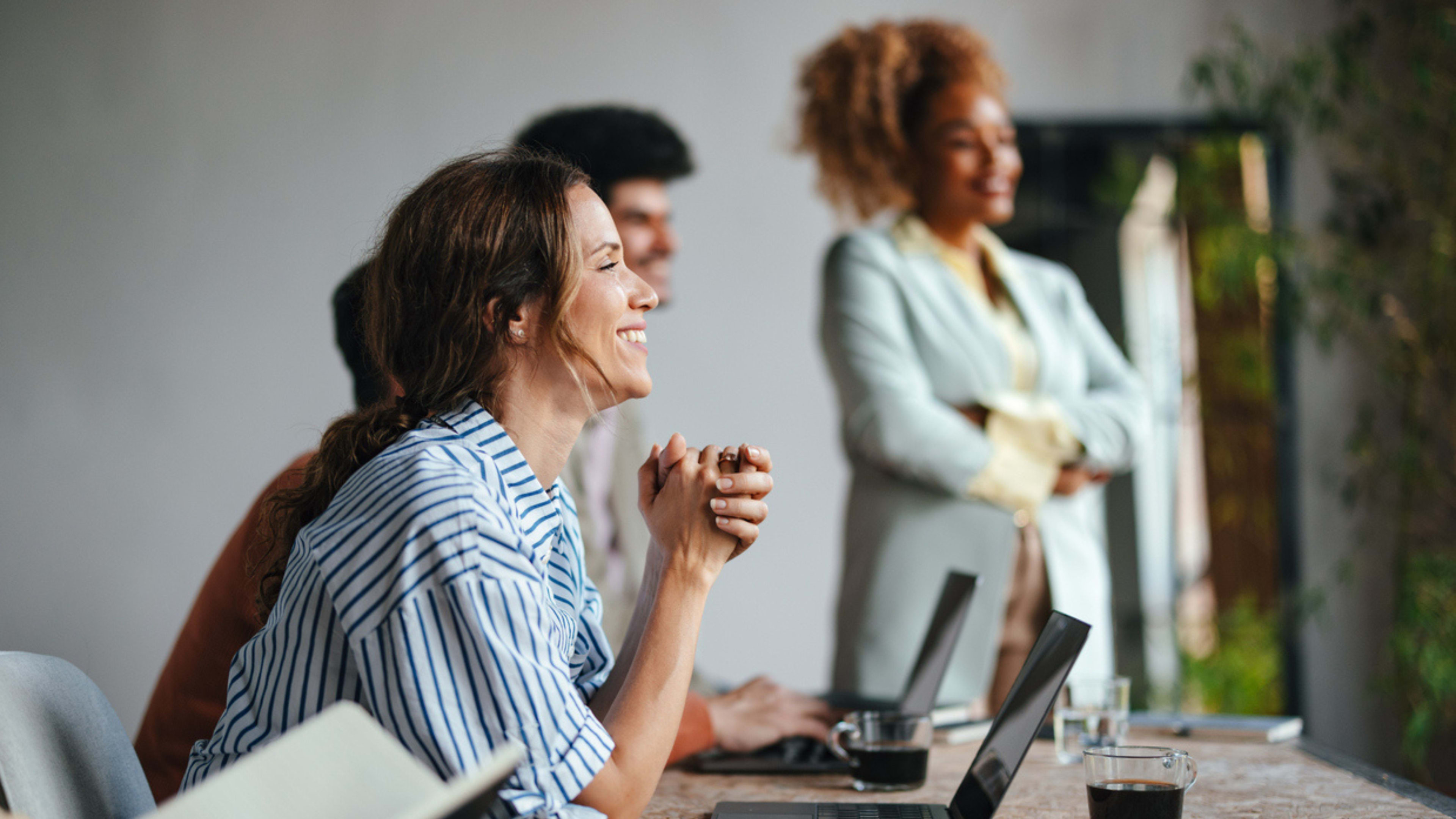 A woman seated a conference table in a collaborative work session.