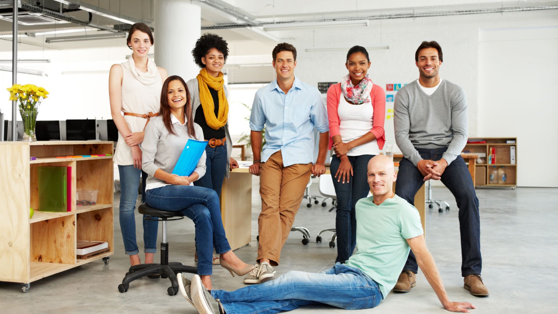 Team of people in a modern workplace looking at camera smiling. 