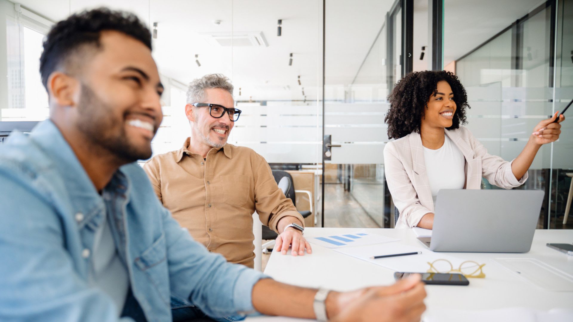 A team smiles broadly during a collaborative session. The image shows moment of genuine enjoyment and connectivity in modern corporate setting, highlighting positive dynamics of workplace interaction