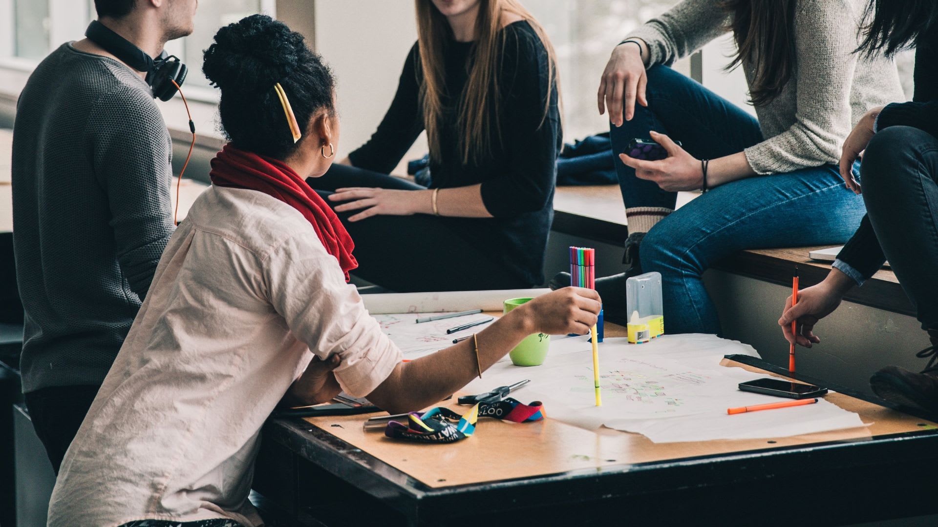 Several people seated at a table, actively engaging in collaborative work.