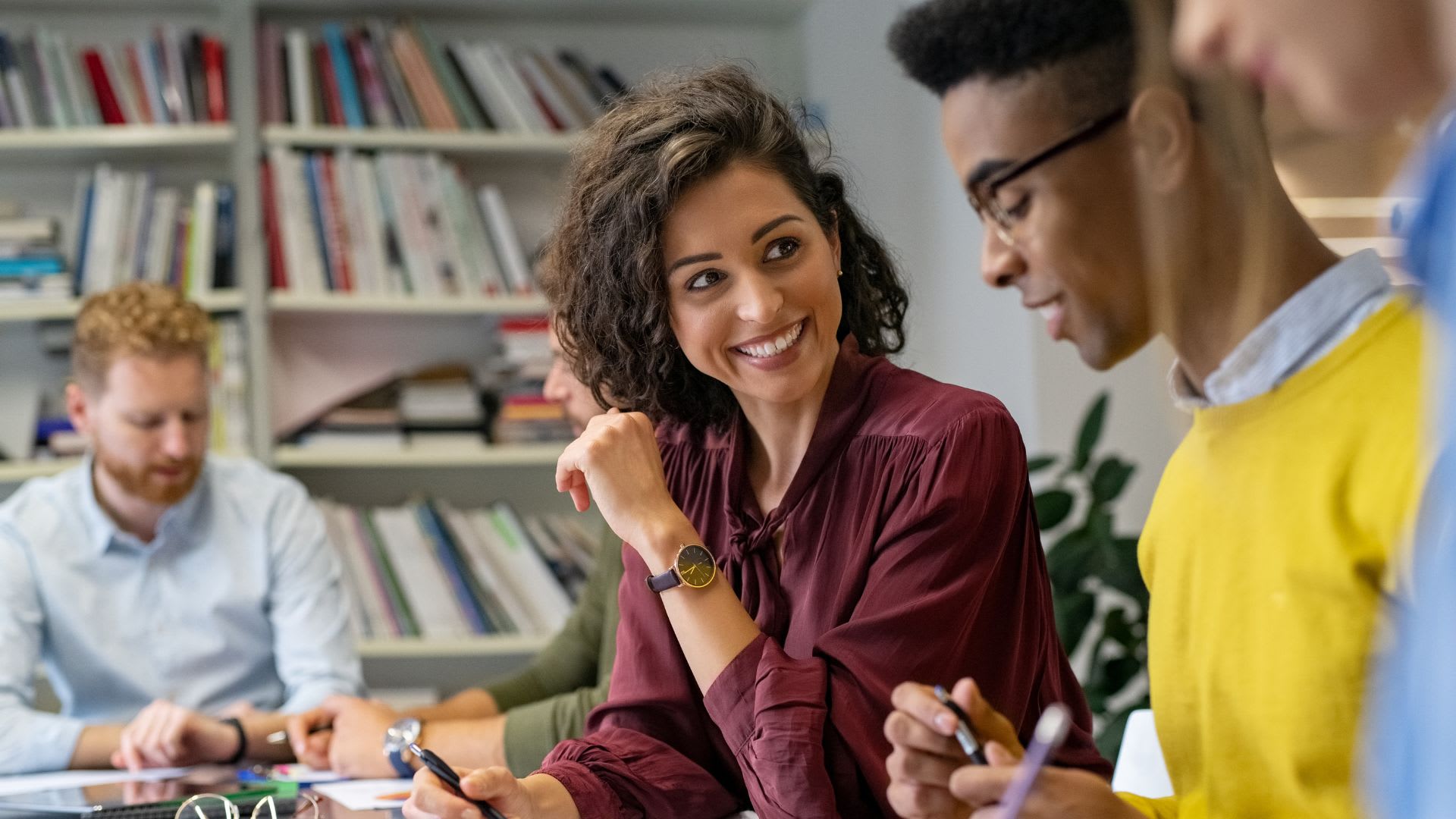 Several people gathered around a table, actively discussing and sharing ideas in a workplace environment.