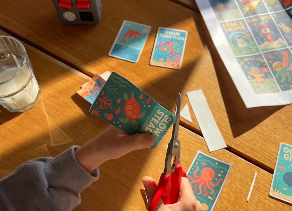 A child cutting printed Yoto MYO labels from a sheet of paper with scissors