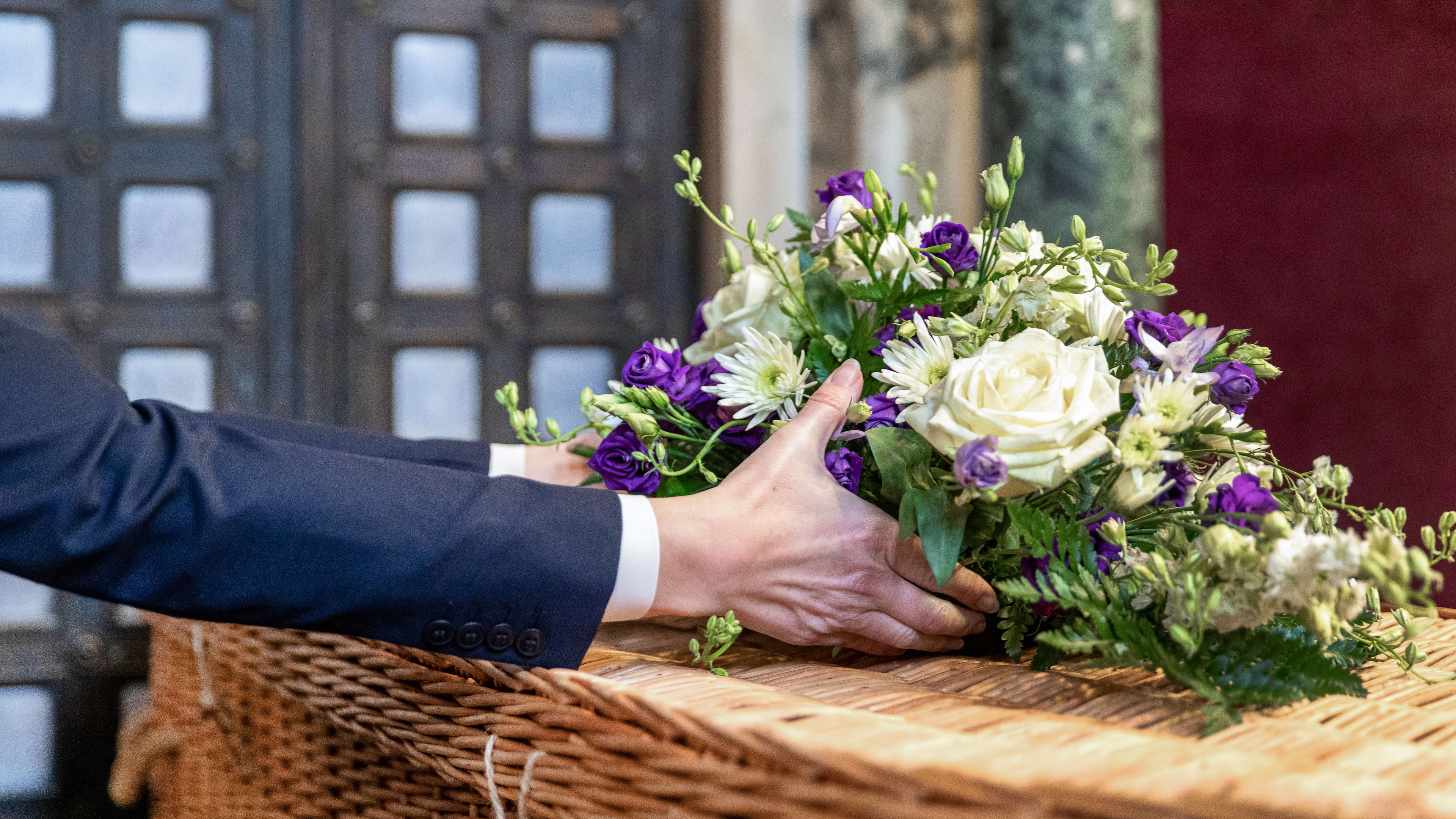 Person putting flowers on a coffin