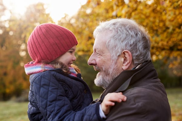 Grandparent holding a smiling grandchild in an Autumn park