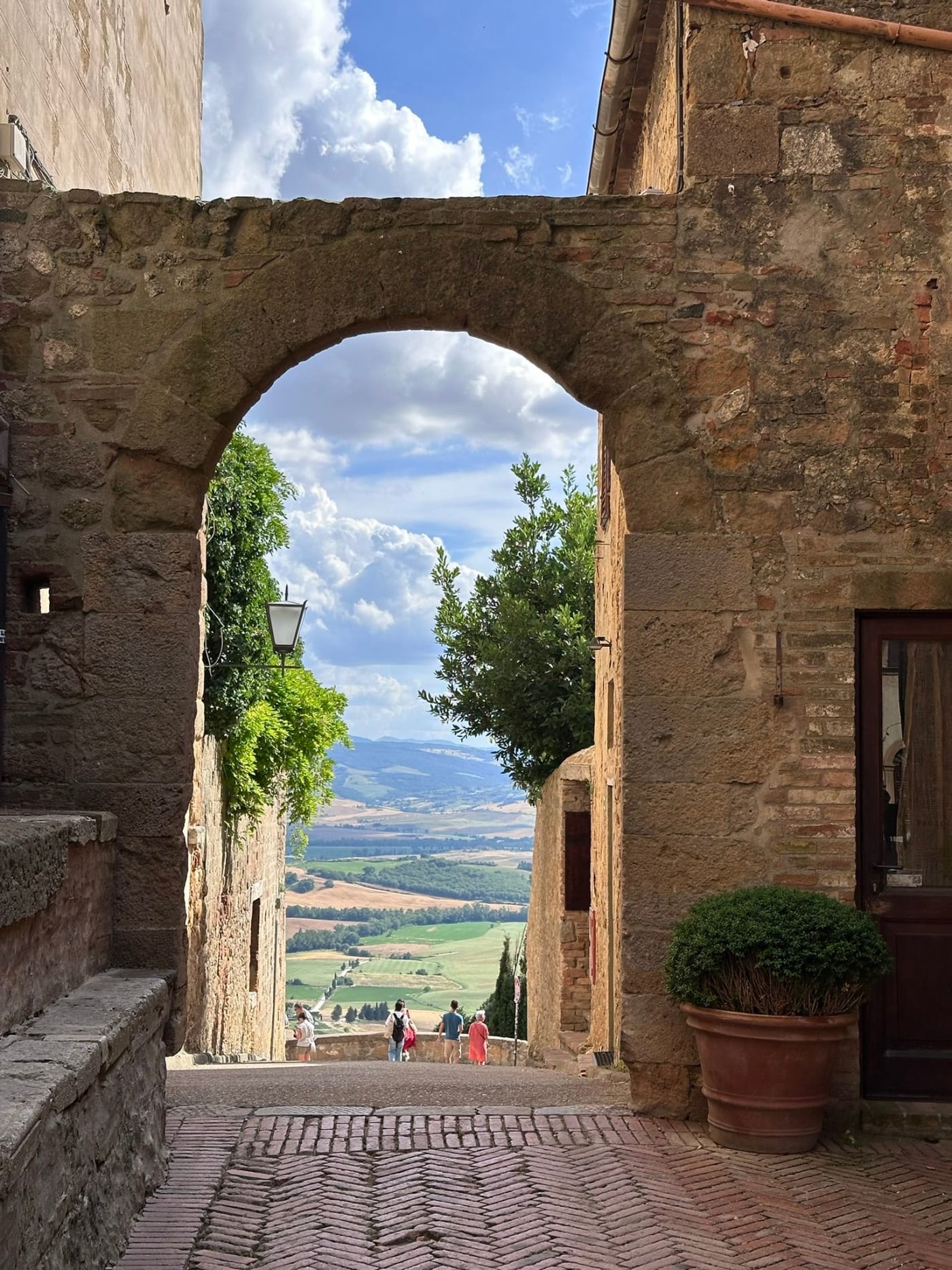 A stone archway in Pienza opening onto the Val d'Orcia countryside