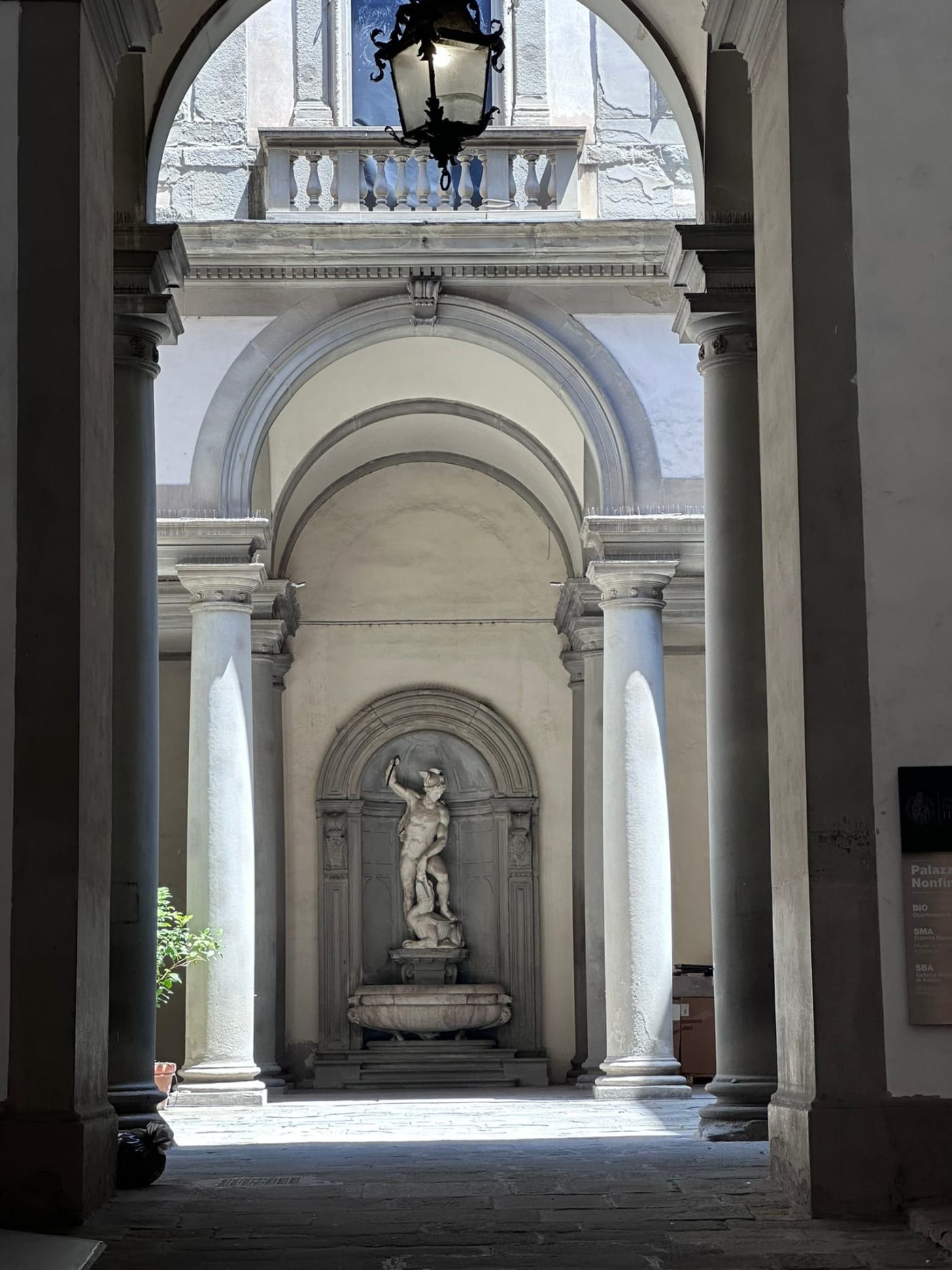 A marble statue in an arched courtyard niche in Florence