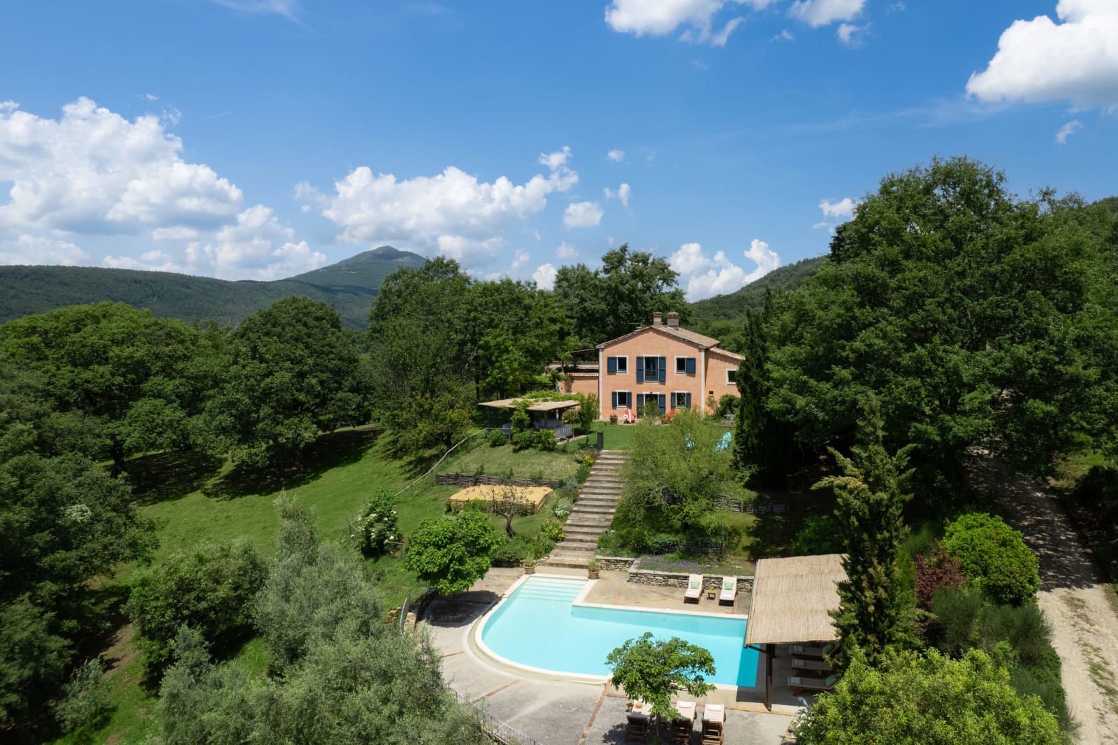 Villa Vetrichina — the farmhouse above its pool, with Monte Cetona beyond