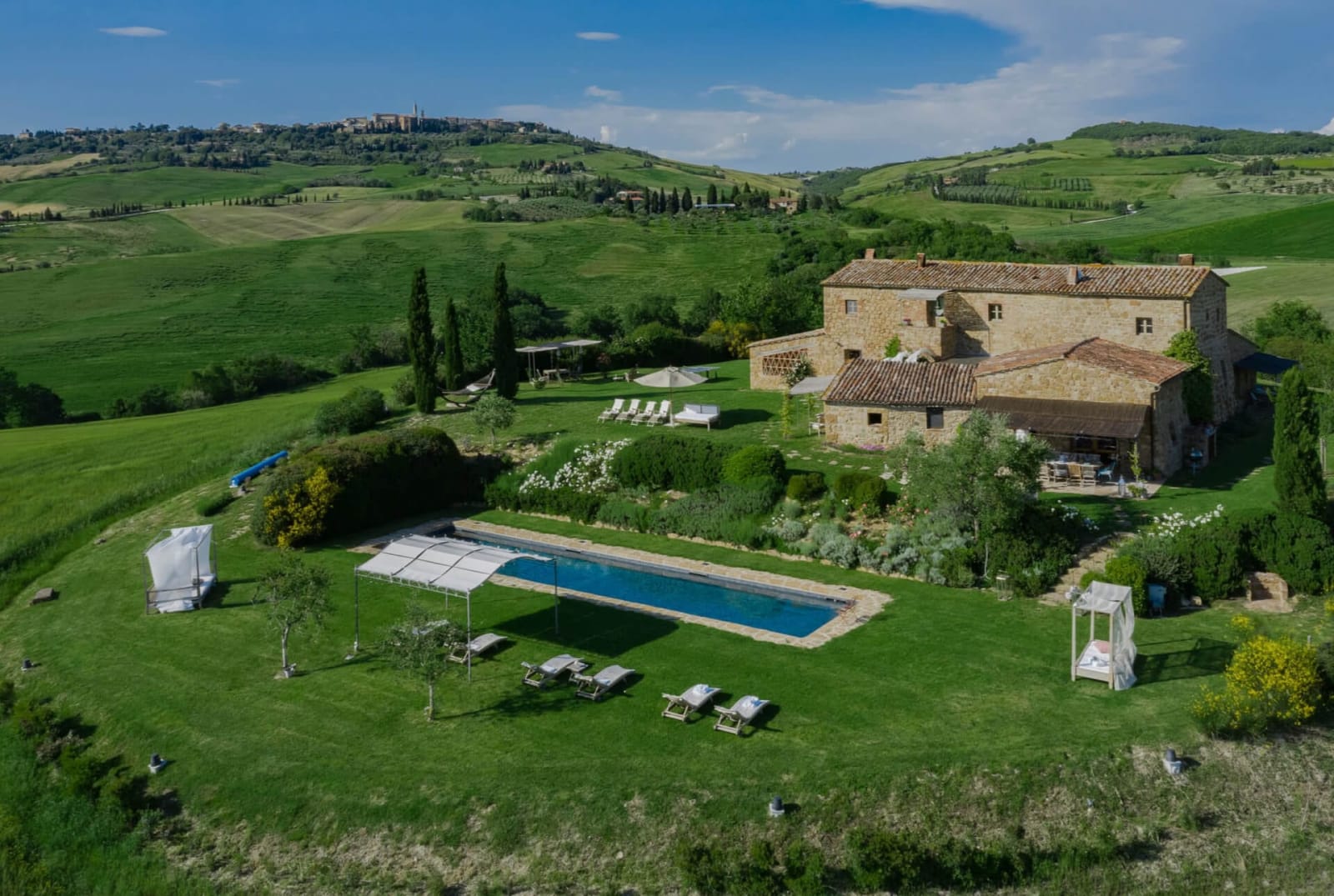Villa delle Sorelle — the stone farmhouse above its long pool in the Val d'Orcia