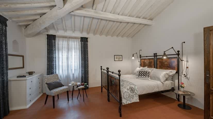 Borgo delle Vigne — a bedroom with a wrought-iron bed and exposed beams