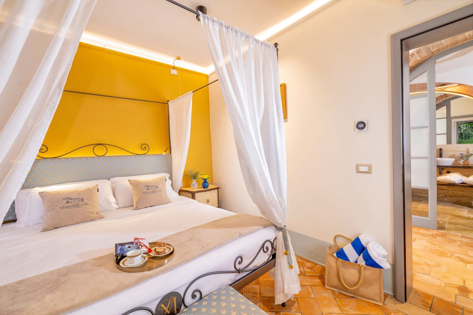Villa Poggio d'Oro — a bed beneath a yellow canopy, with garden doors