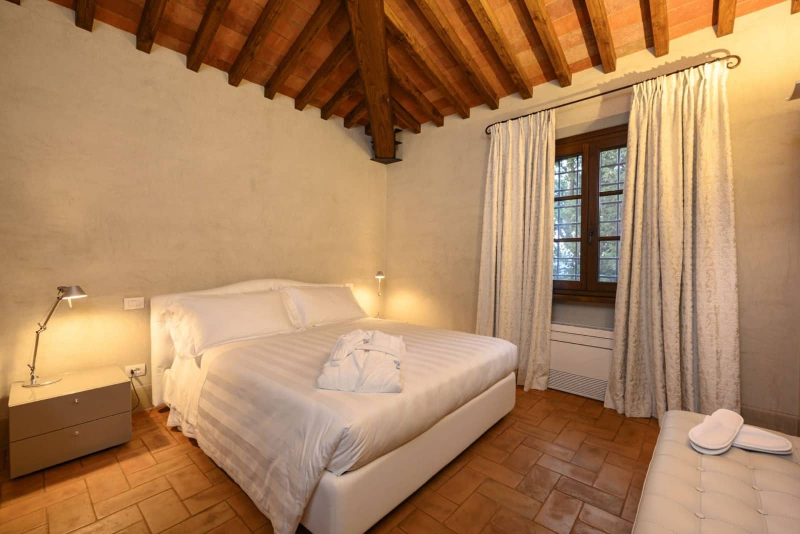 Villa San Bartolomeo — a bedroom with a cream tufted headboard
