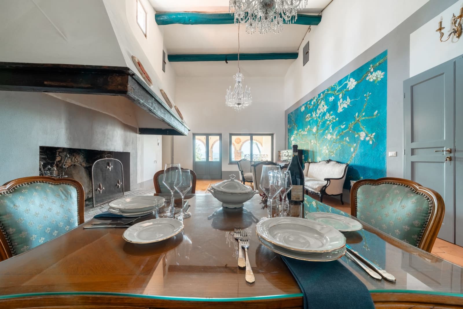 Villa Poggio d'Oro — a dining table beneath the almond-blossom mural
