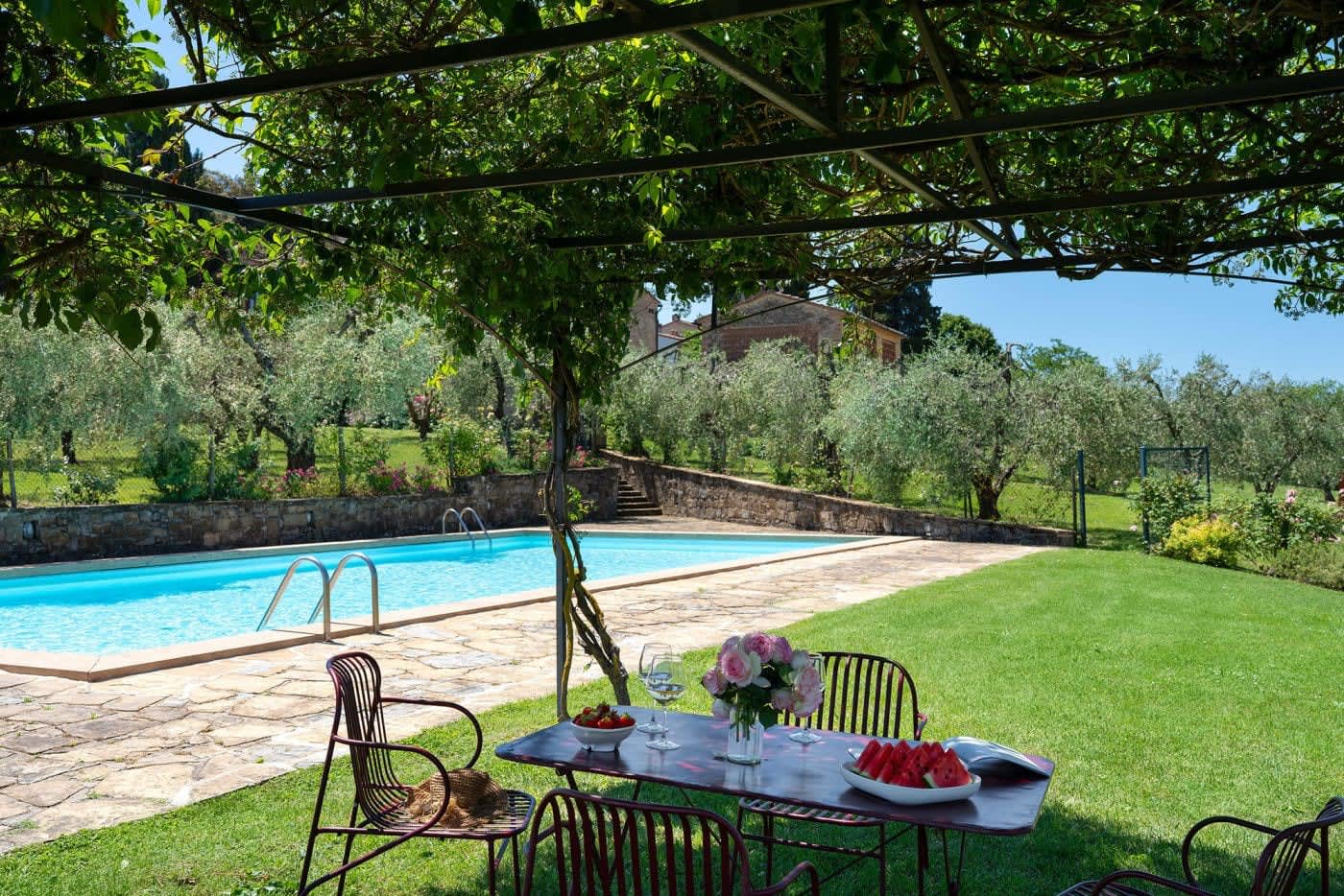 Villa Castellaro — a table under the pergola beside the pool