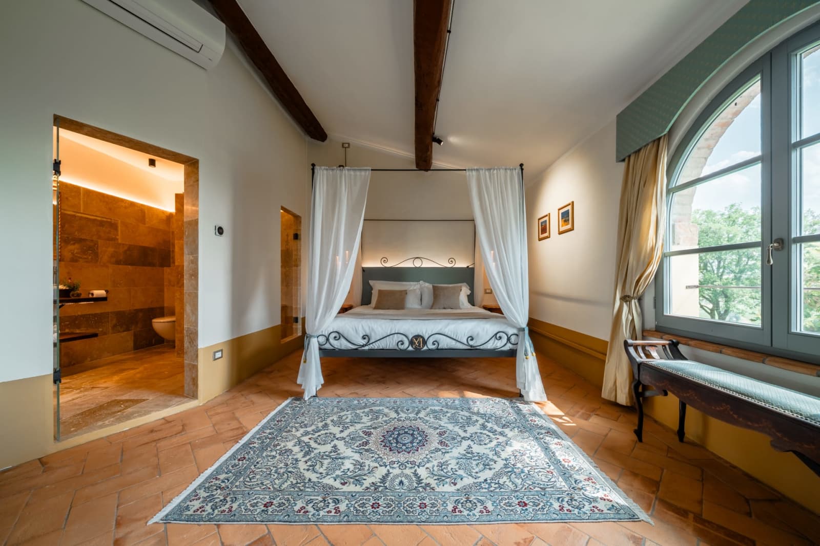 Villa Poggio d'Oro — a canopy bed beneath chestnut beams