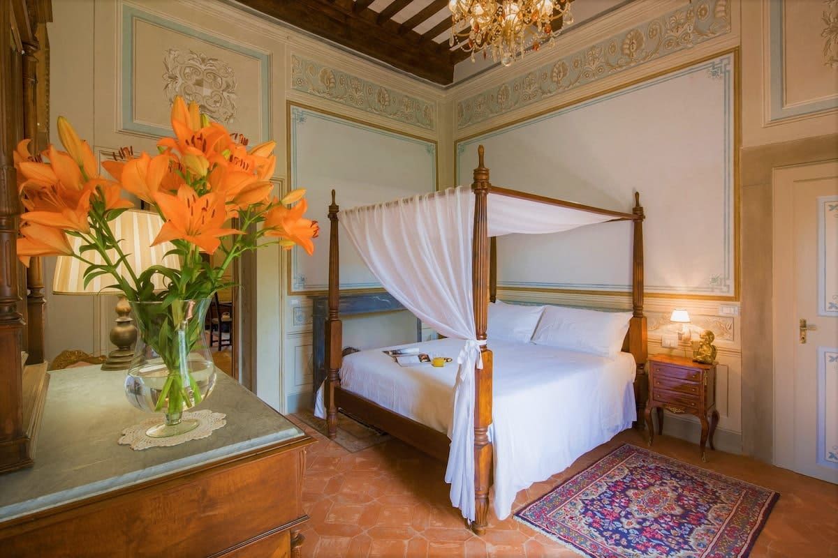 Villa della Cappella — a four-poster bedroom with fresh lilies