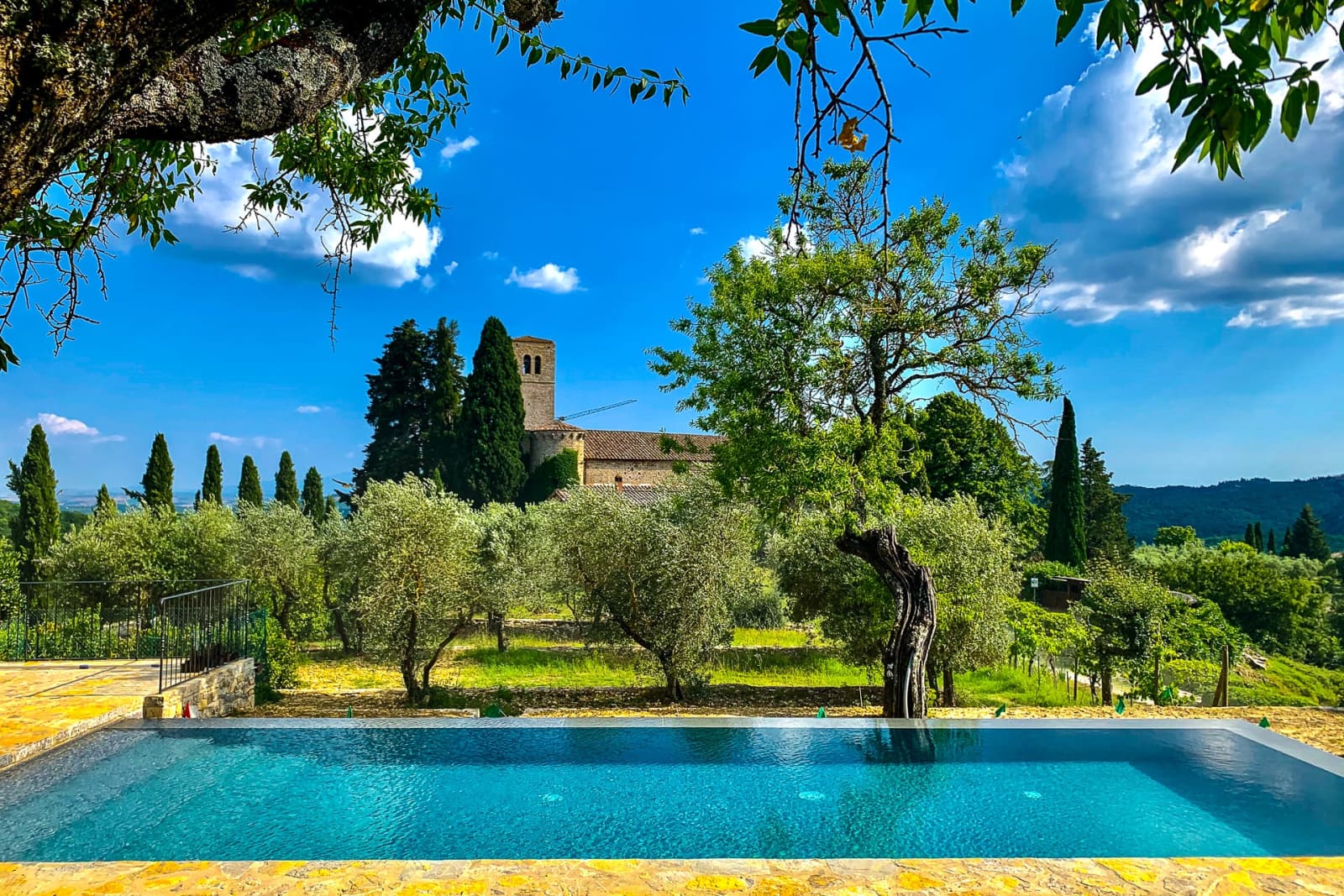 Casa dell'Erta — the pool among olive trees, with the castle beyond