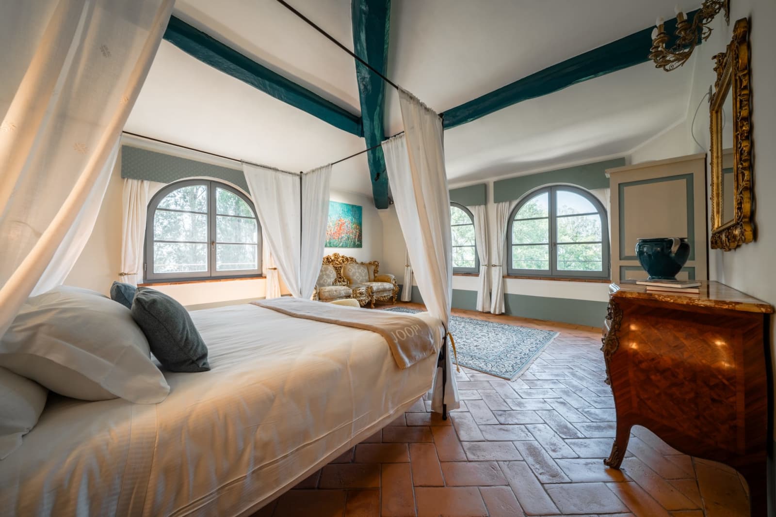 Villa Poggio d'Oro — a canopy bed beneath blue-painted beams
