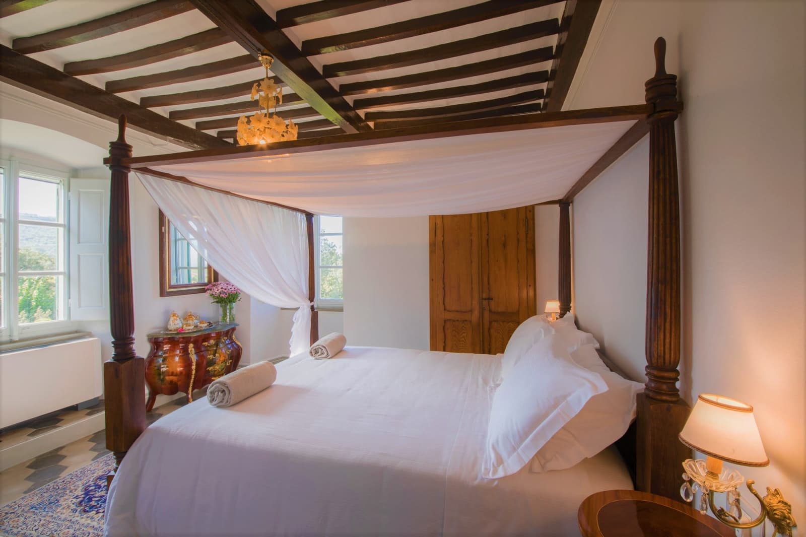 Villa della Cappella — a beamed-ceiling bedroom with canopy bed