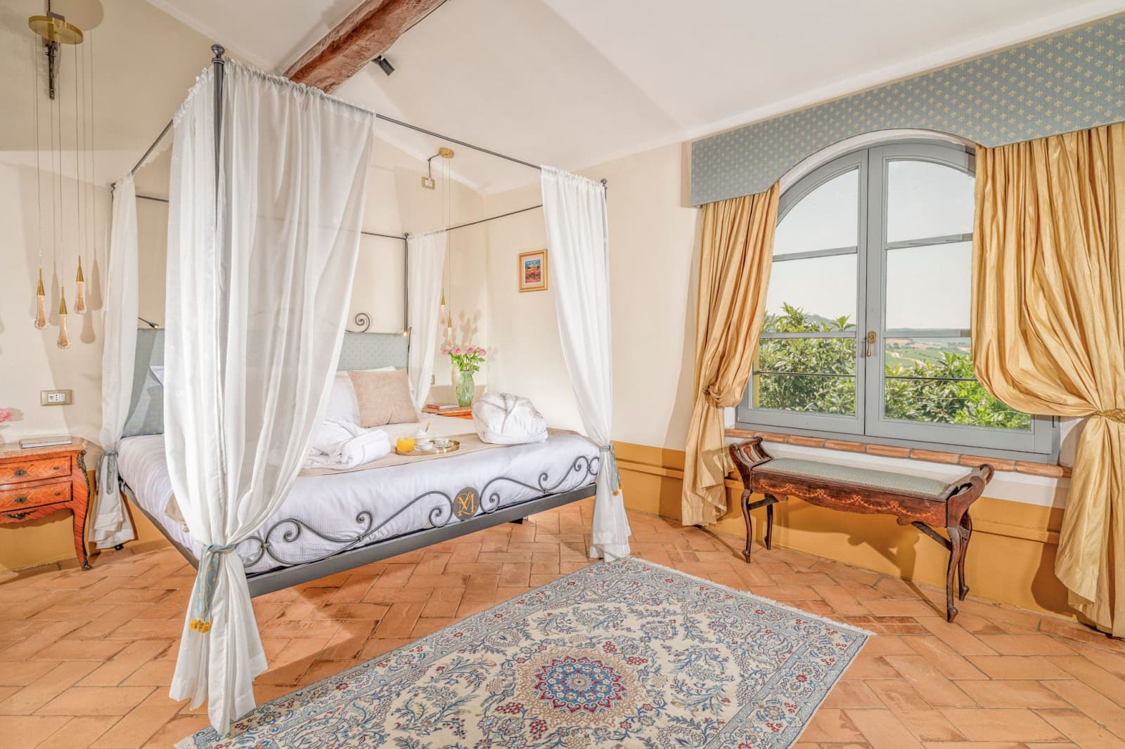 Villa Poggio d'Oro — a canopy bed with a bench and blue rug