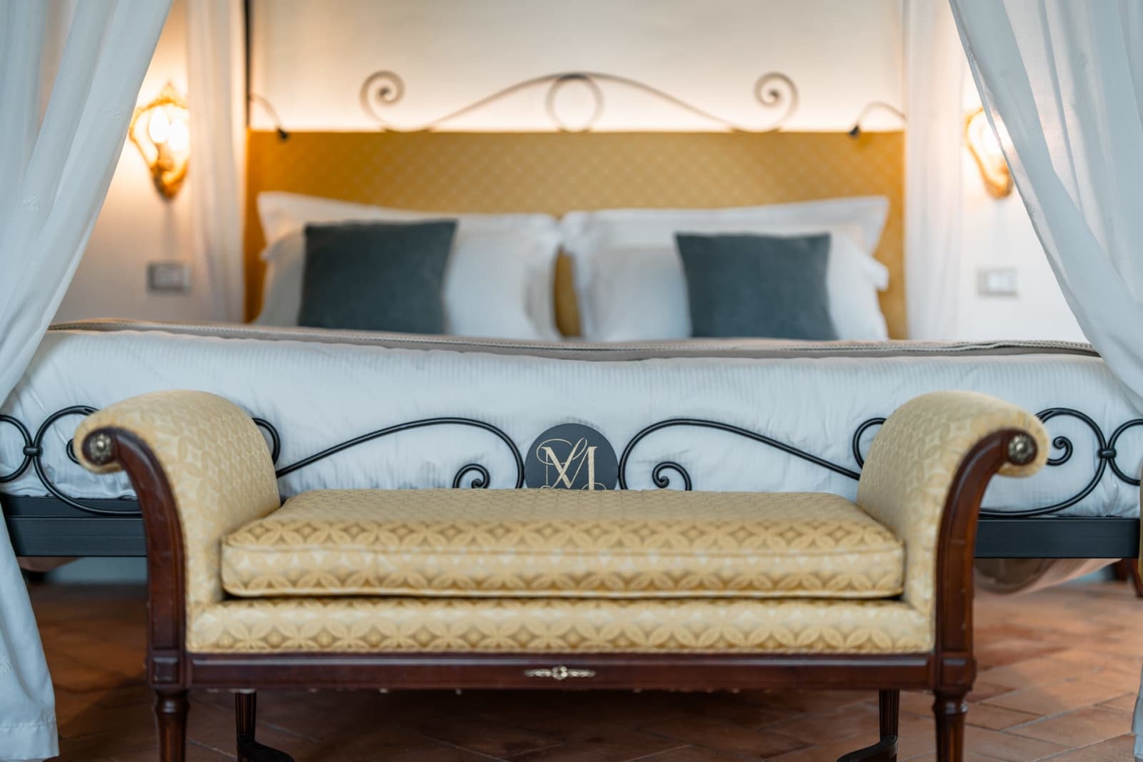 Villa Poggio d'Oro — a wrought-iron bed with an upholstered bench