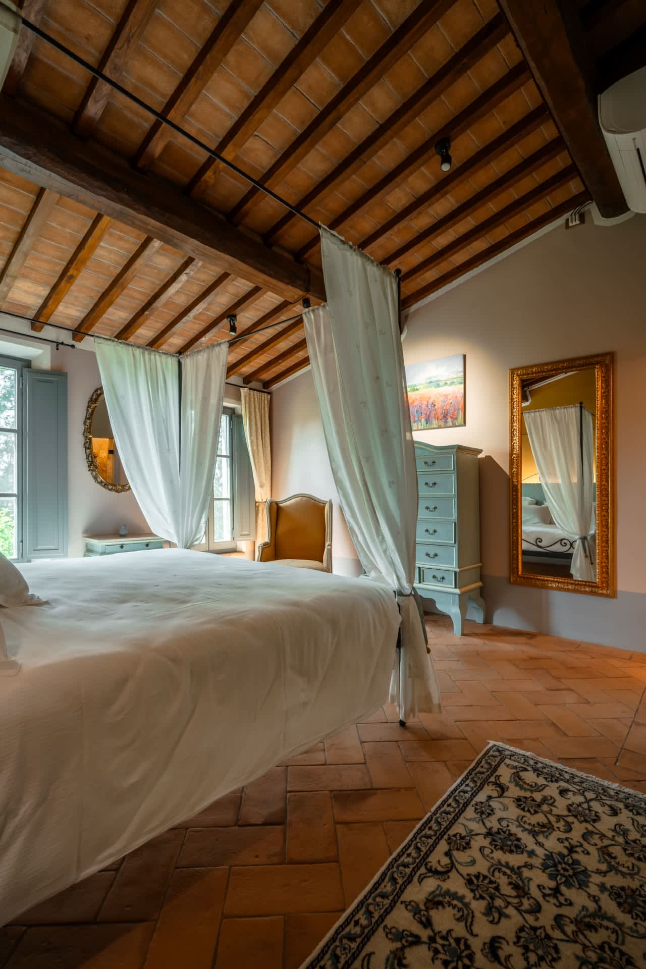 Villa Poggio d'Oro — a canopy bed beside a painted cabinet