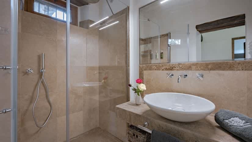 Borgo delle Vigne — a bathroom with a vessel sink, exposed beams reflected in the mirror