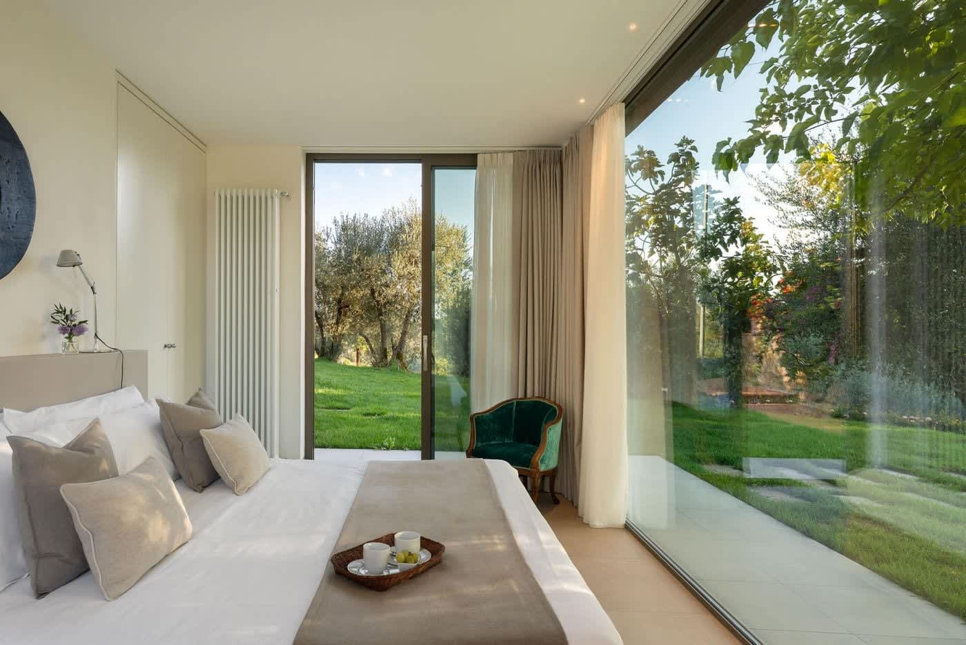 Casa Lilia — a bedroom with floor-to-ceiling glass onto the garden