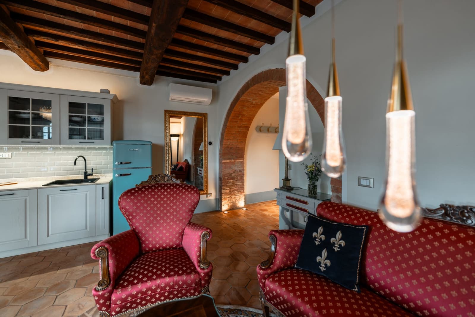 Villa Poggio d'Oro — red armchairs beneath glass pendant lights