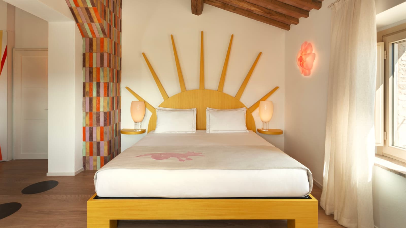 Podere Mastrojanni — a bedroom with a sunburst headboard and mosaic pilaster