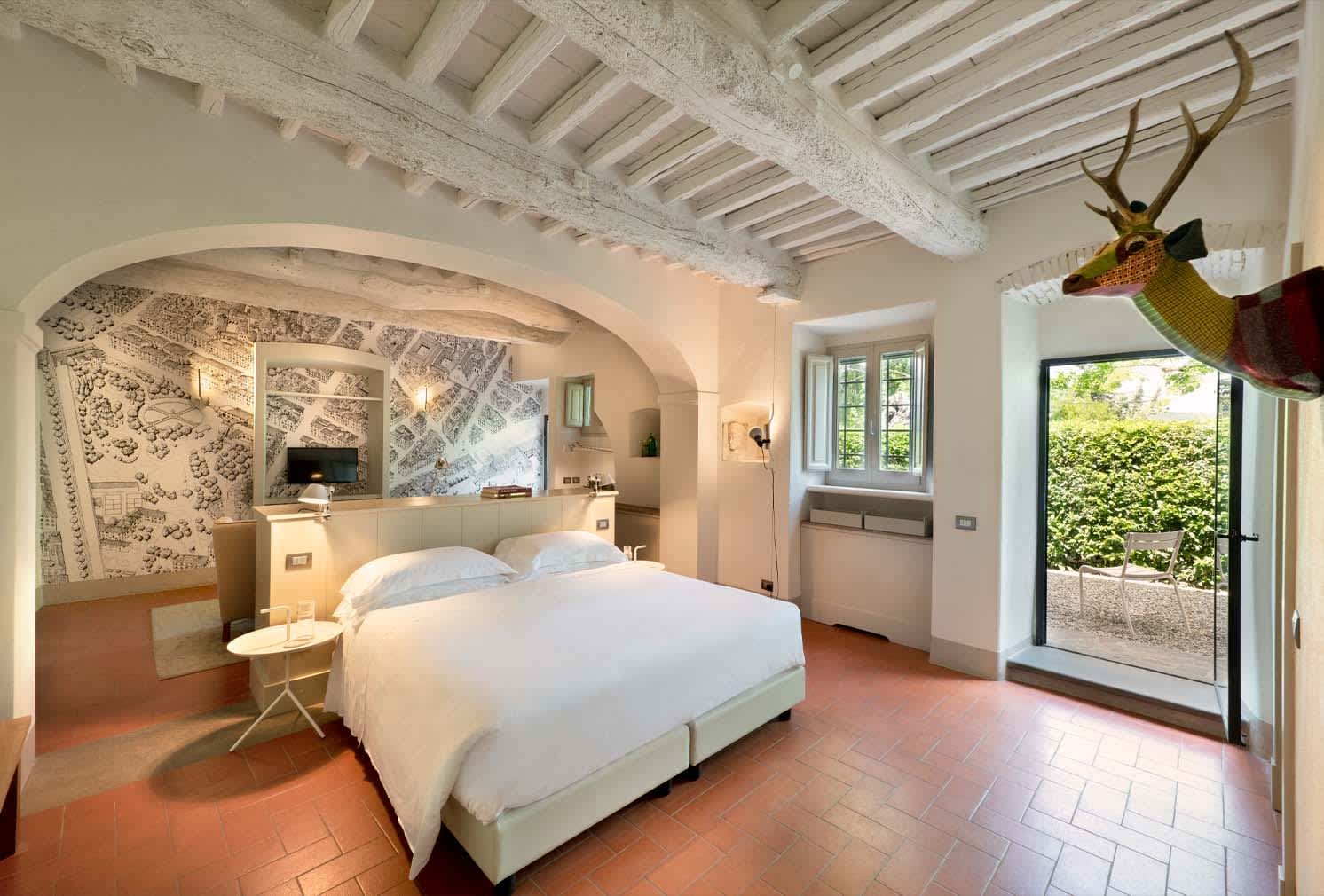 Casale Gherardi — a bedroom with beamed ceiling opening onto the garden