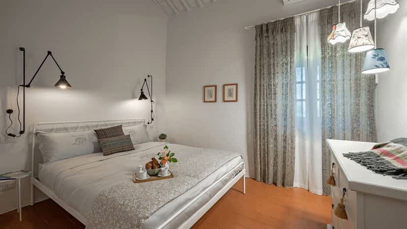 Borgo delle Vigne — a bedroom with floral pillows and grey curtains