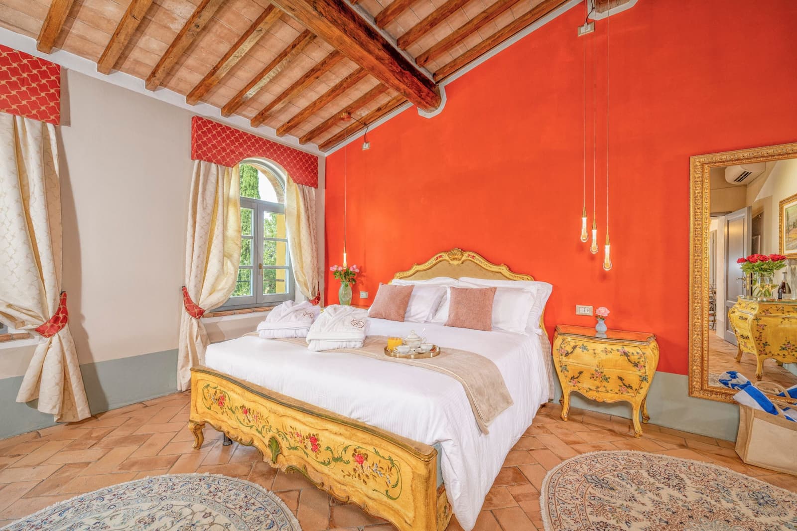 Villa Poggio d'Oro — a bedroom with terracotta-red walls and a gilded bed