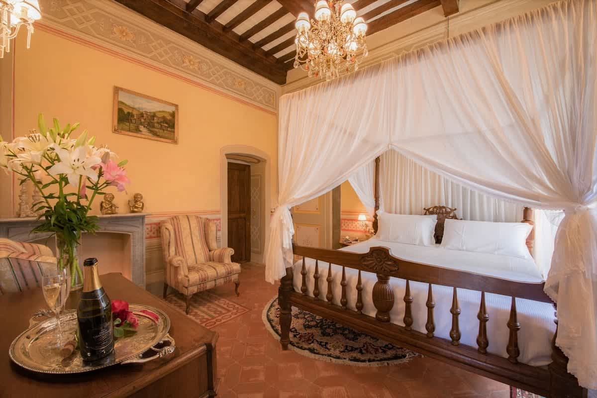 Villa della Cappella — a four-poster bedroom beneath a chandelier